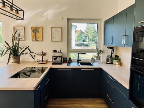 a kitchen with blue cabinets and a sink and a window at Gemütliches Ferienhaus im idyllischen Falkensee in Falkensee
