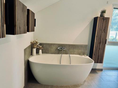 a large white tub in a bathroom with a window at Gemütliches Ferienhaus im idyllischen Falkensee in Falkensee