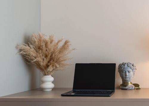 a table with a laptop and a vase with a head at Aurelia Pristina in Pristina