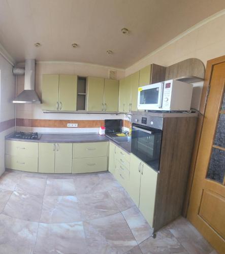 a kitchen with yellow cabinets and a white microwave at Хостел Твій Дім в Пирятині in Pyryatyn