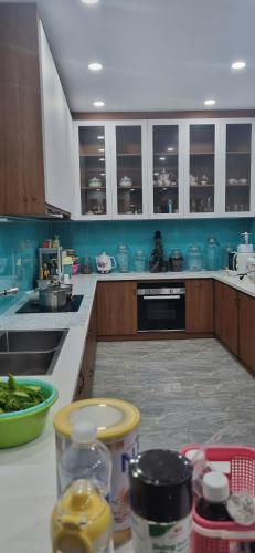 a kitchen with blue walls and white cabinets and a counter at Homestay Thule in Ho Chi Minh City