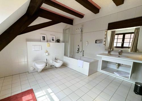 a bathroom with a toilet and a tub and a sink at Herzogskelter Hotel & Restaurant in Güglingen