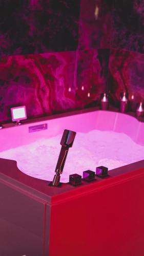 a hot tub in a room with pink lighting at Nos Limites Room in Ollioules