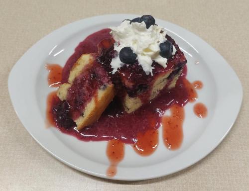 a white plate with a piece of cake with blueberry sauce at Hotel&Restaurant Gasthof zur Post Eisenerz in Eisenerz