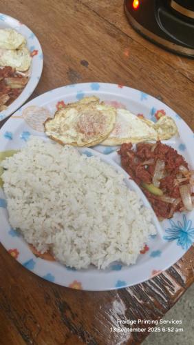 a plate of rice and meat on a wooden table at Mavriz Transient in La Trinidad