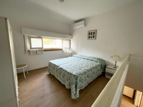 a white bedroom with a bed and a window at Villetta con giardino di fronte al mare in Principina a Mare