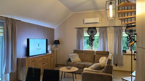 a living room with a couch and a tv at Jeleń Residence in Jeleniów