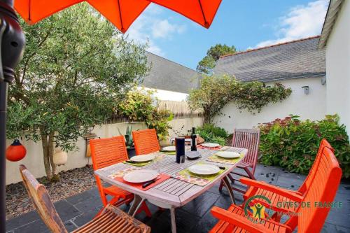 una mesa de madera con sillas y una sombrilla en Villa kormoran, en Carnac