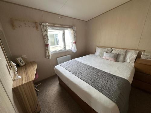 a bedroom with a large bed and a window at Chichester Lakeside holiday park in Merston