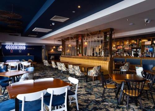 a restaurant with tables and chairs and a bar at Chichester Lakeside holiday park in Merston