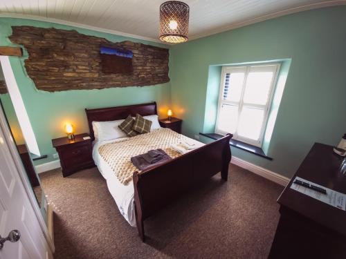 a bedroom with a bed and a stone wall at Jabajak Vineyard with Rooms in Llanboidy