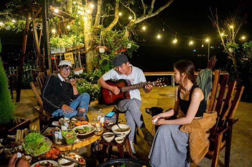 a group of people sitting around a table playing guitar at Mây Nhà Tuii - Homestay in Da Lat in Ấp Ða Lợi