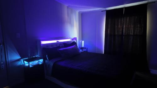 a dark room with a bed with a purple light at Faith short term rental in Romulus