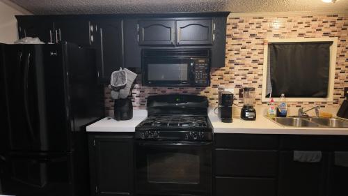 a kitchen with black cabinets and a stove and a sink at Faith short term rental in Romulus