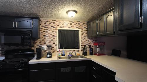 a kitchen with black cabinets and a sink and a stove at Faith short term rental in Romulus