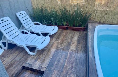 two lounge chairs and a swimming pool on a deck at Casa de 2 suites com piscina e churrasqueira in Armacao dos Buzios