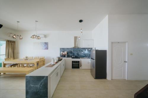a kitchen with white walls and a black refrigerator at Phaladise Beach Villa at Phala Beach, Ban Chang in Rayong