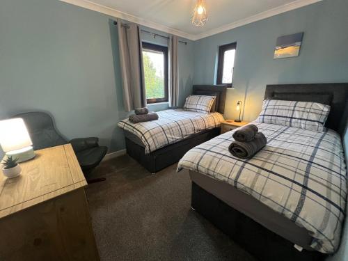 a bedroom with two beds and a desk and a chair at Superb Comfy 2 Bed House, Responsive & Caring Hosts Free WiFi & Parking, Close to MK Centre, Train Station, Santander, Network Rail by Webbhill Stays in Milton Keynes