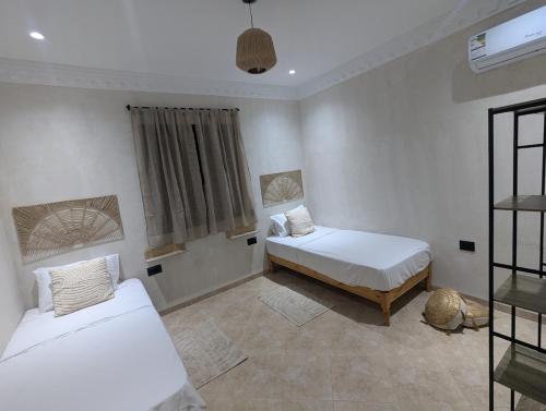 a bedroom with two beds and a window at Magnifique villa typique avec piscine privée in El Guecheïne