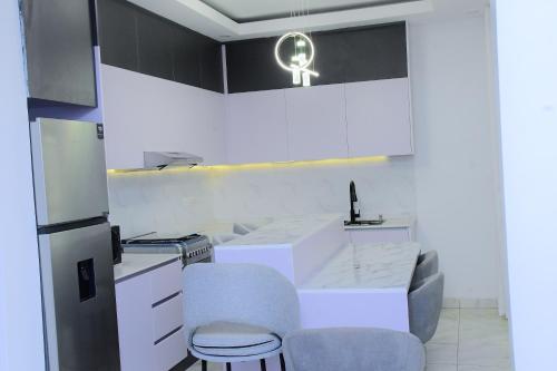 a kitchen with a white counter and chairs in it at Kayiranga Apartments in Bugesera