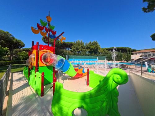a playground with a green slide at a park at Campeggio del Forte in Marina di Bibbona