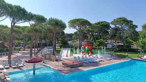 a pool at a resort with chairs and a water park at Appartamenti Campeggio del Forte in Marina di Bibbona