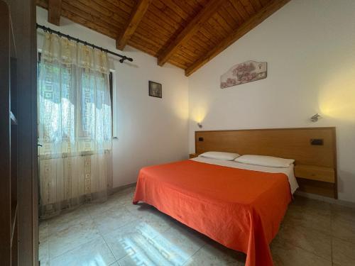 a bedroom with a bed with a orange bedspread at Villa Rosi&Maria in Coccorino
