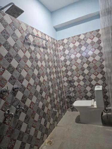 a bathroom with a toilet and a tiled wall at Mns residency in Imphal