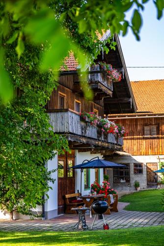 a house with a balcony with a table and an umbrella at Thalerbauer Ferienwohnungen in Wackersberg