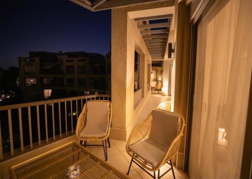 two chairs and a cat sitting on a balcony at night at Luxury Rooms in the Heart of Pyramids in Kafr Ghaţāţī