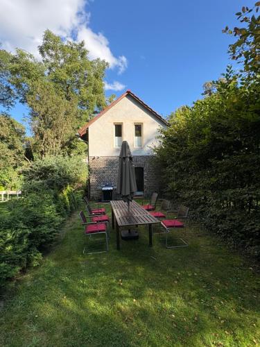 a table and chairs with an umbrella in a yard at Remise an der Rennbahn - umzäuntes Anwesen mit Parkplätzen, AmzonPrime, Netflix, Wii, PS2 in Hoppegarten