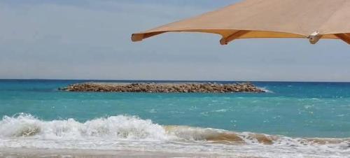 a beach with an umbrella and the ocean at شاليه ثلاث غرف مكيف ومجهز بالكامل in ‘Atāqah