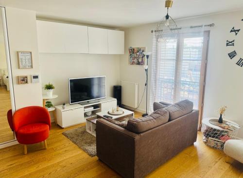 a living room with a couch and a television at Cosy Appart Rueil - 50m2 Parking Souterrain - proche Paris - Business et loisir in Rueil-Malmaison