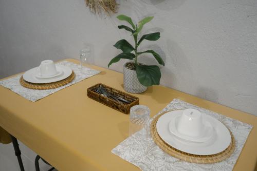 Una mesa amarilla con dos platos blancos y una planta. en Dayon place near the airport, en Puerto Princesa City