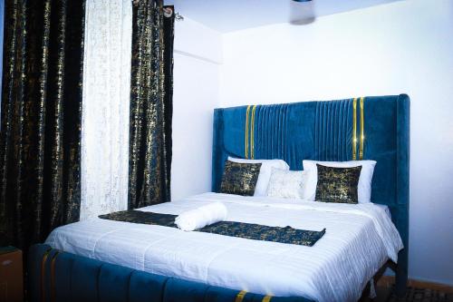 J and A Haven BnB- Langata Road opposite Uhuru gardens memorial park في نيروبي: سرير مع اللوح الأمامي الأزرق والملاءات والوسائد البيضاء