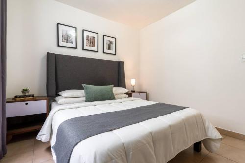 a bedroom with a large bed with a green pillow at Depto moderno cerca Estadio GNP y Aeropuerto in Mexico City