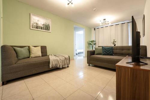 a living room with two couches and a flat screen tv at Depto moderno cerca Estadio GNP y Aeropuerto in Mexico City