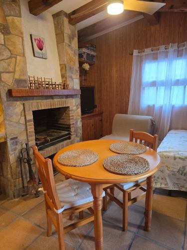 a table and chairs in a room with a fireplace at Can Marisu in Cabrils