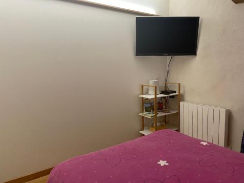 une chambre avec un lit violet et une télévision à écran plat dans l'établissement Chambre à Châtillon, à Châtillon