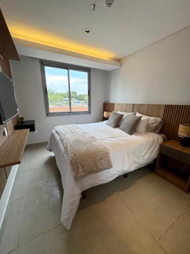 a bedroom with a large bed and a window at Edificio Emerald II - Asunción in Asuncion