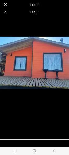 a house with two windows on a wooden deck at Cabañas almendra in Quellón