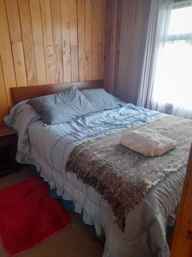 a bed with a pillow on it with a window at Cabañas almendra in Quellón