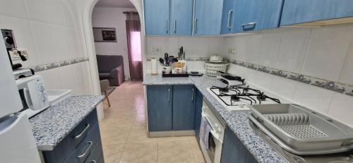 a kitchen with blue cabinets and a stove top oven at Tres Playas Apartment in Puerto de Mazarrón