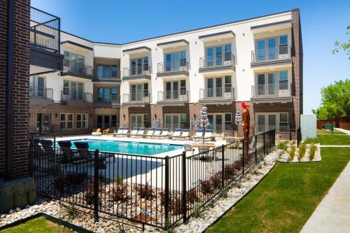 an apartment building with a swimming pool in front of a building at LUX Apt 2 Min to TCU Pool & Gym! in Fort Worth
