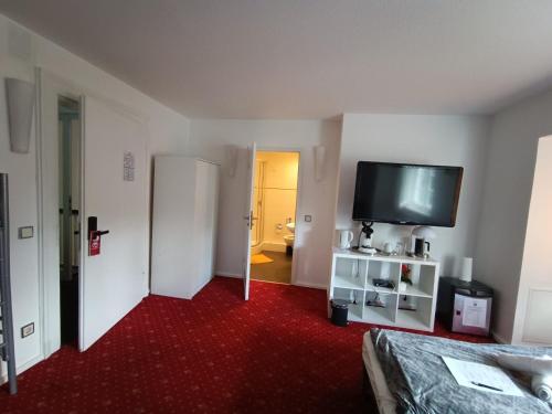 a room with a bed and a flat screen tv at Die Villa Hotel in Leverkusen
