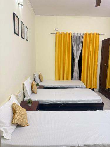 twee bedden in een kamer met gele gordijnen bij Elite Hostel- A Perfect Stay for Working Professional,Travellers in Pune
