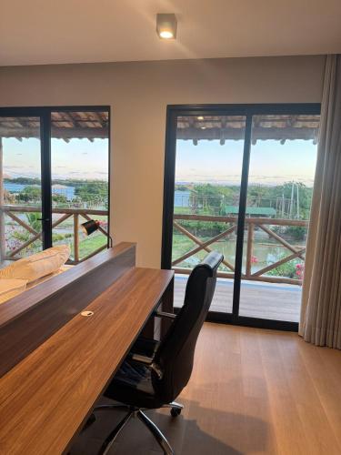a office with a desk and a chair and windows at Casa Aloha in Petrolina