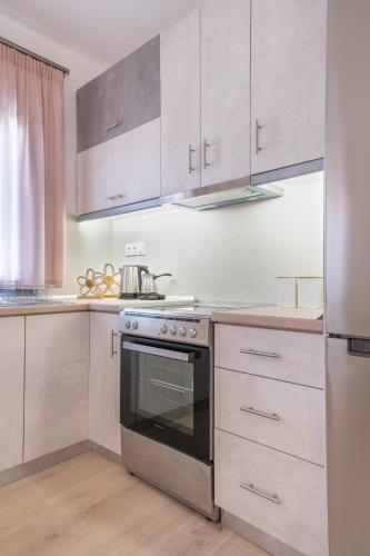 a kitchen with white cabinets and a stainless steel oven at Myrina Retreat - Golden Sun in Mirina