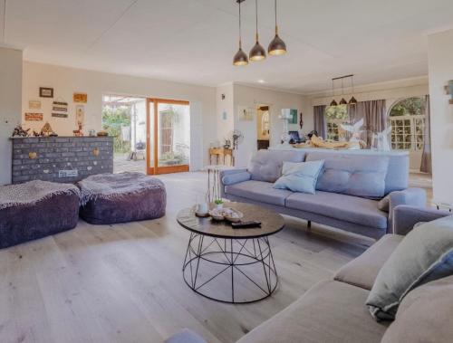ein Wohnzimmer mit einem blauen Sofa und einem Tisch in der Unterkunft Idylla Guest Home in Kenton on Sea