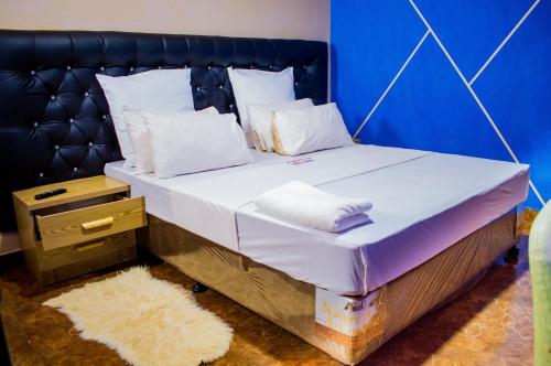 a large bed with white sheets and a blue wall at Kurhulla Guest House in Chimoio